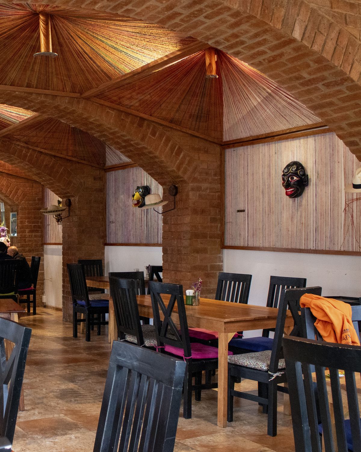 Comedor interior con mesas largas de madera bajo bóvedas de ladrillo en Los Priostes