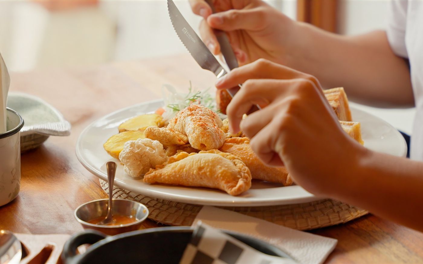 Comensales sirviéndose empanaditas del Ecuador con ají en la mesa de Los Priostes