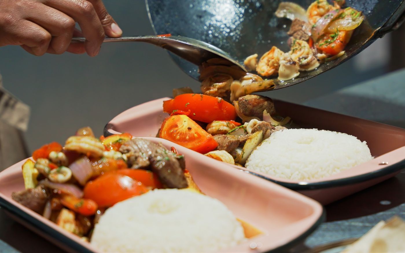 Salteado de lomo y vegetales servido desde el wok a un plato con arroz en Los Priostes