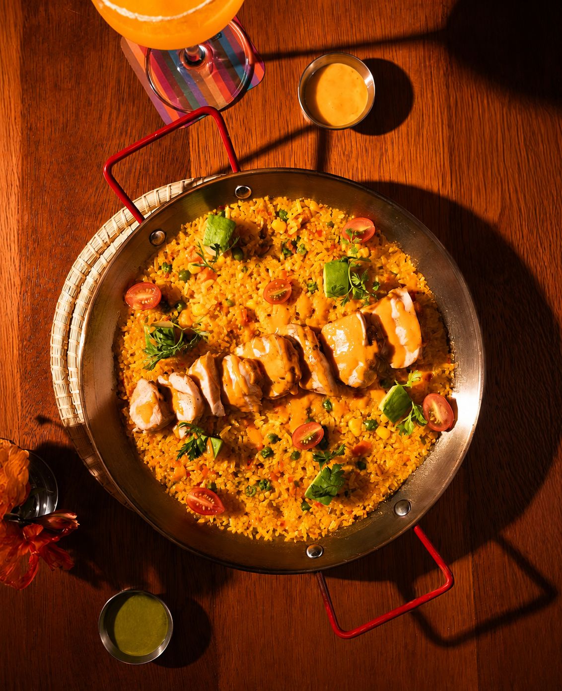 Arroz con pollo de fiesta servido en paila de metal con maduro, vegetales y ají, en Los Priostes Cuenca